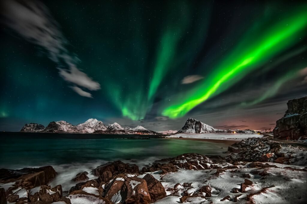 Captivating view of the Northern Lights over snow-covered Lofoten Islands at night.